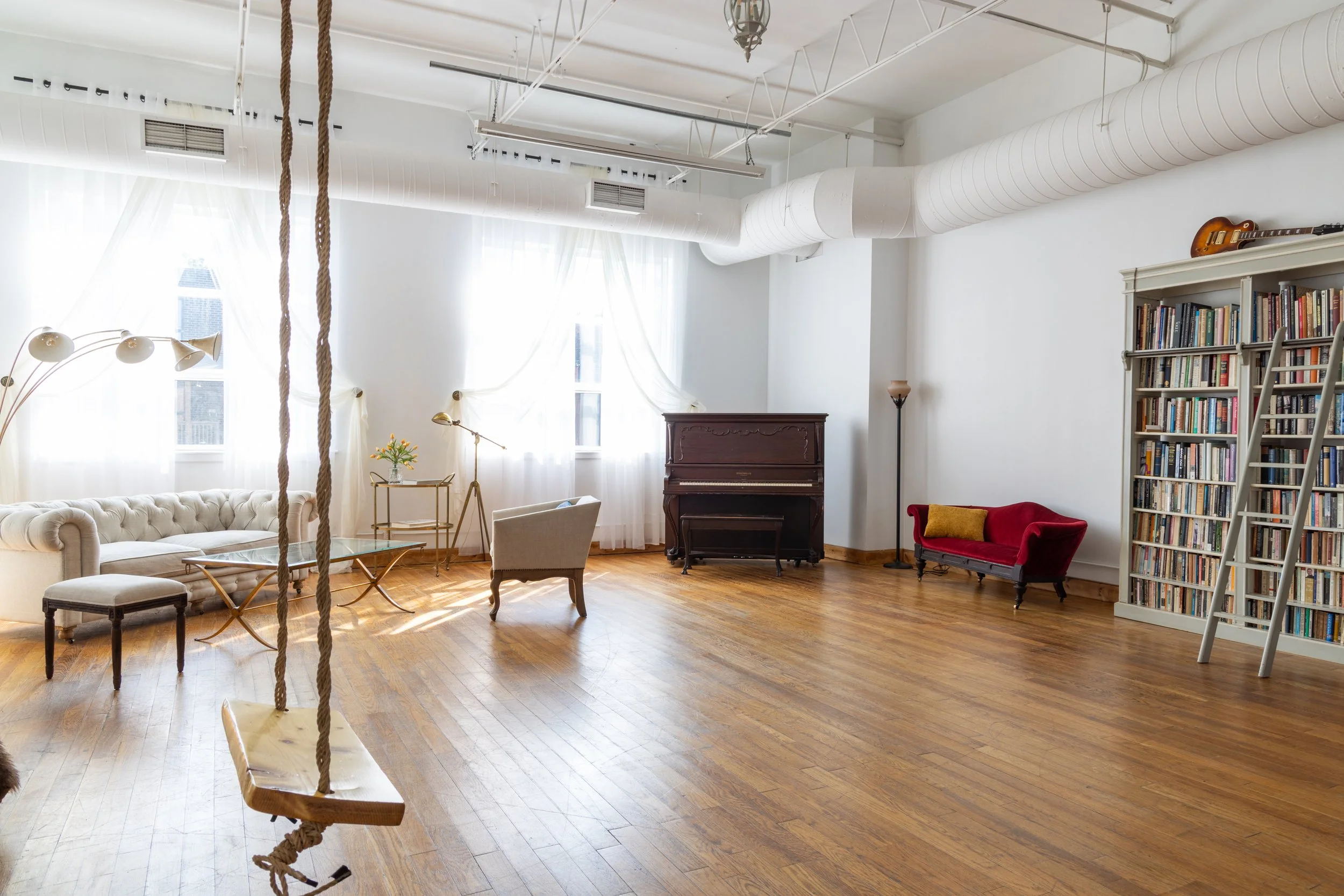 Studio Three with vintage decor, draped windows, and a bookshelf.