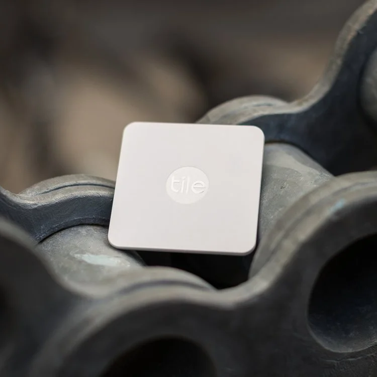 A white square Tile tracker placed on top of a water pipe fitting.