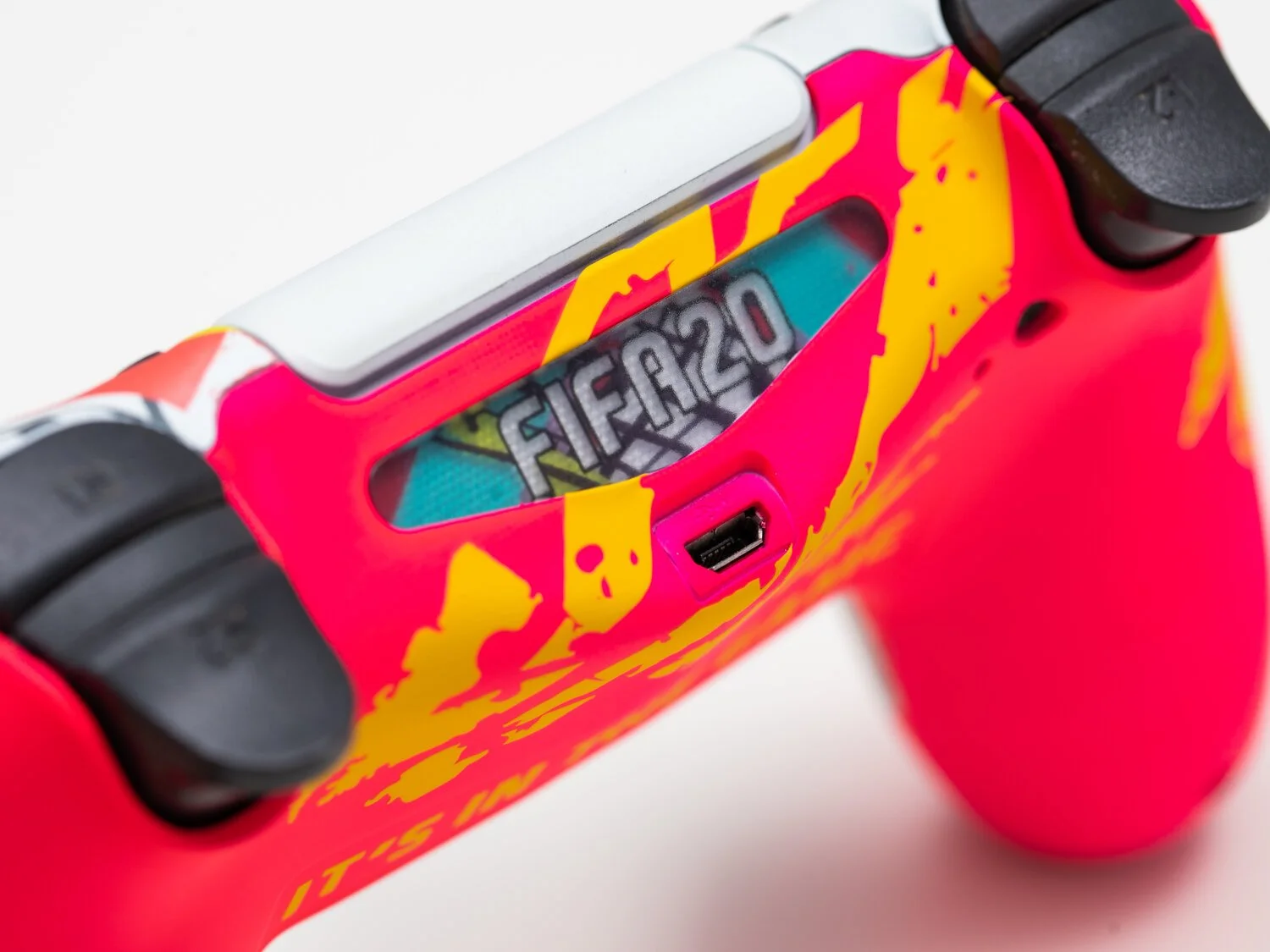 Close-up of a colorful gaming controller with a visible Nintendo Switch cartridge labeled "FIFA 20" inserted in the slot.