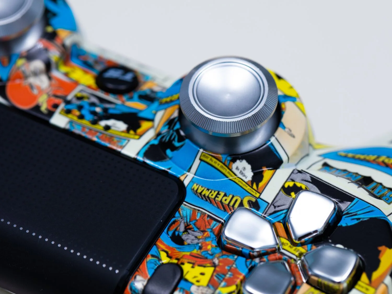Close-up of a video game controller with a Marvel comic book design and a smartphone on top.