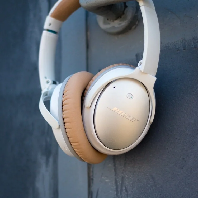 White Bose headphones with beige ear cushions on a dark gray surface.