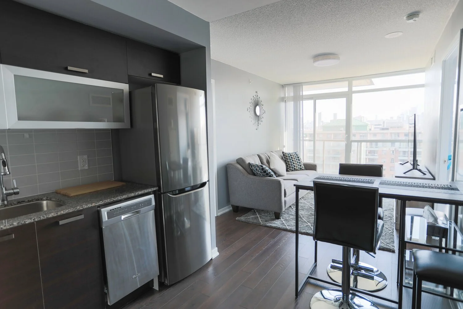 Modern open-concept living space with kitchen and sitting area, large windows, and city view.