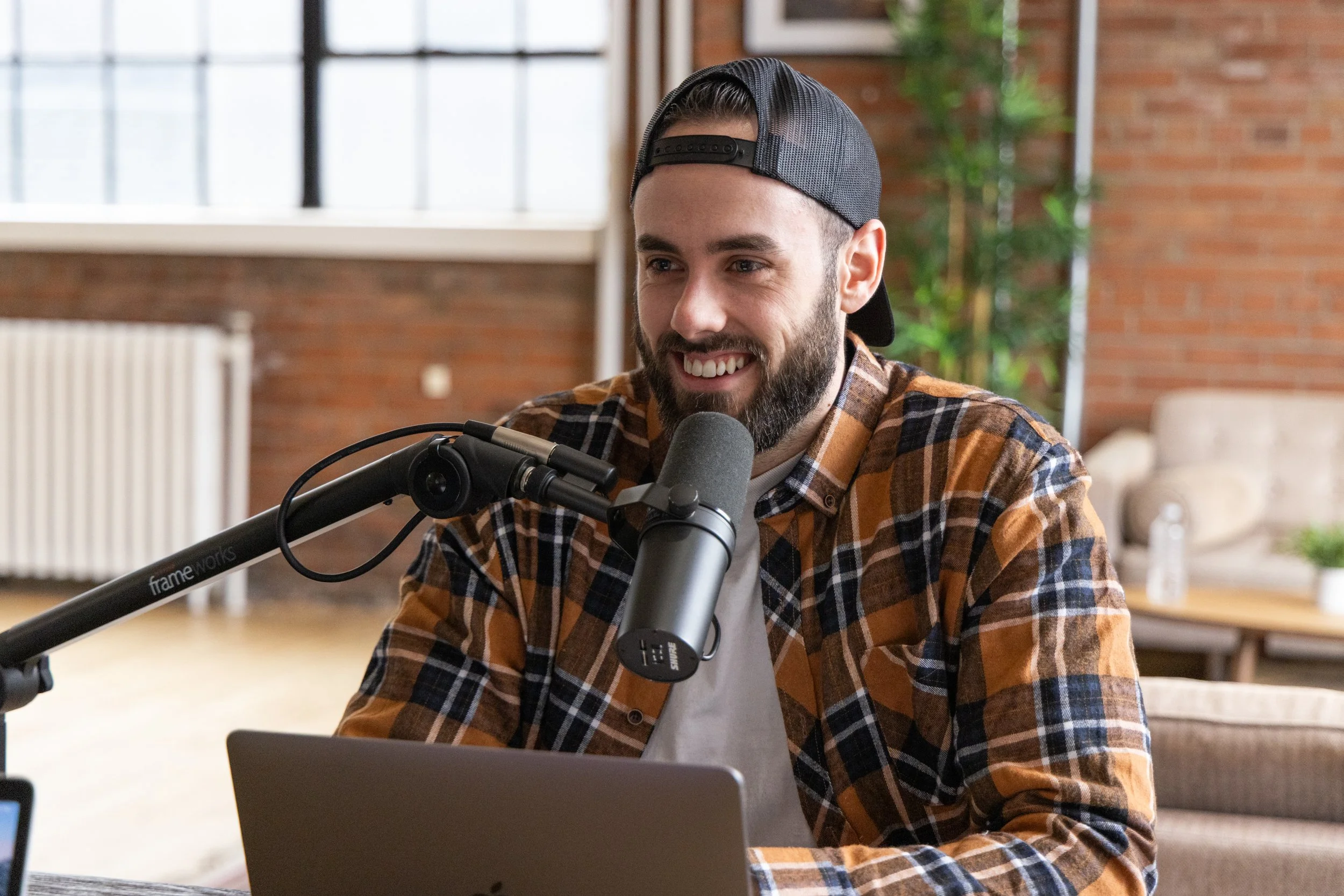 Liam recording a podcast episode with a microphone and laptop.