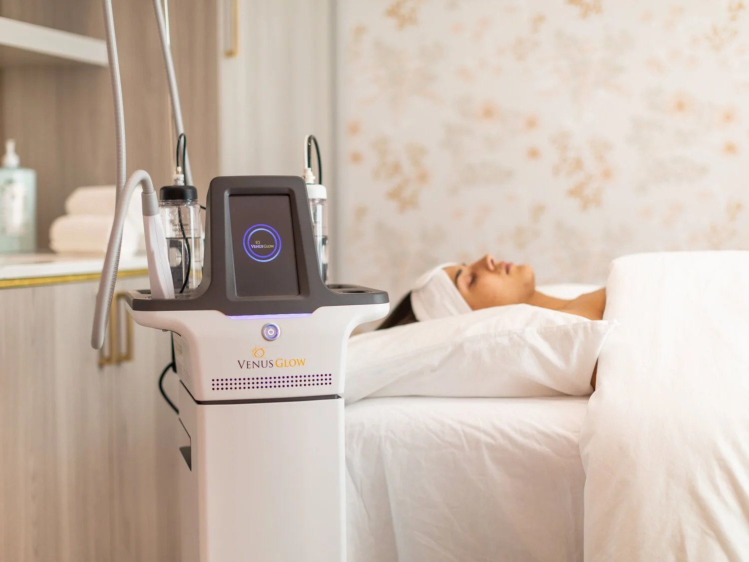 Woman receiving a facial treatment with Venus Glow skincare technology in a spa room.