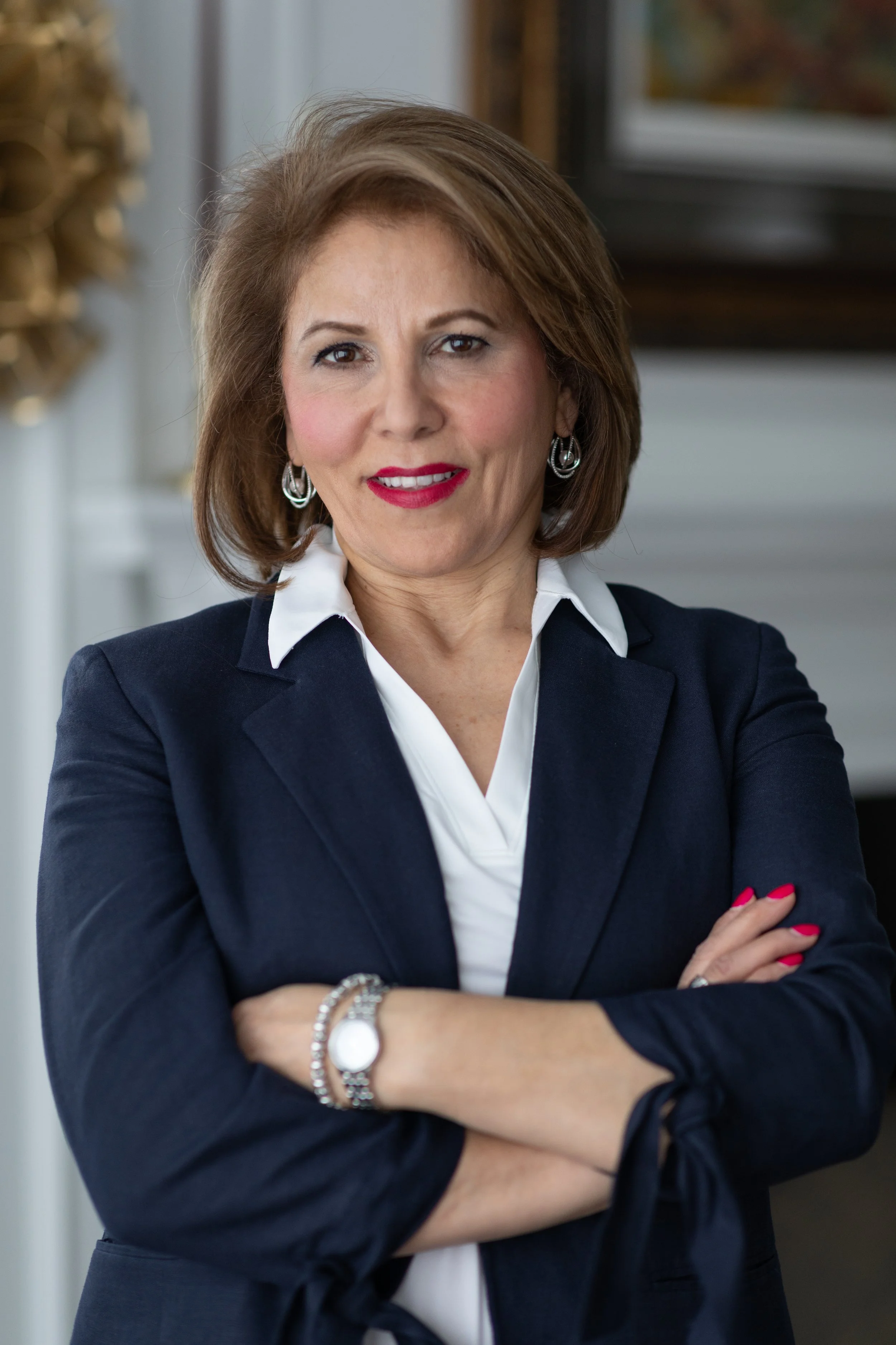 Confident woman in a navy blazer smiling in an office setting.